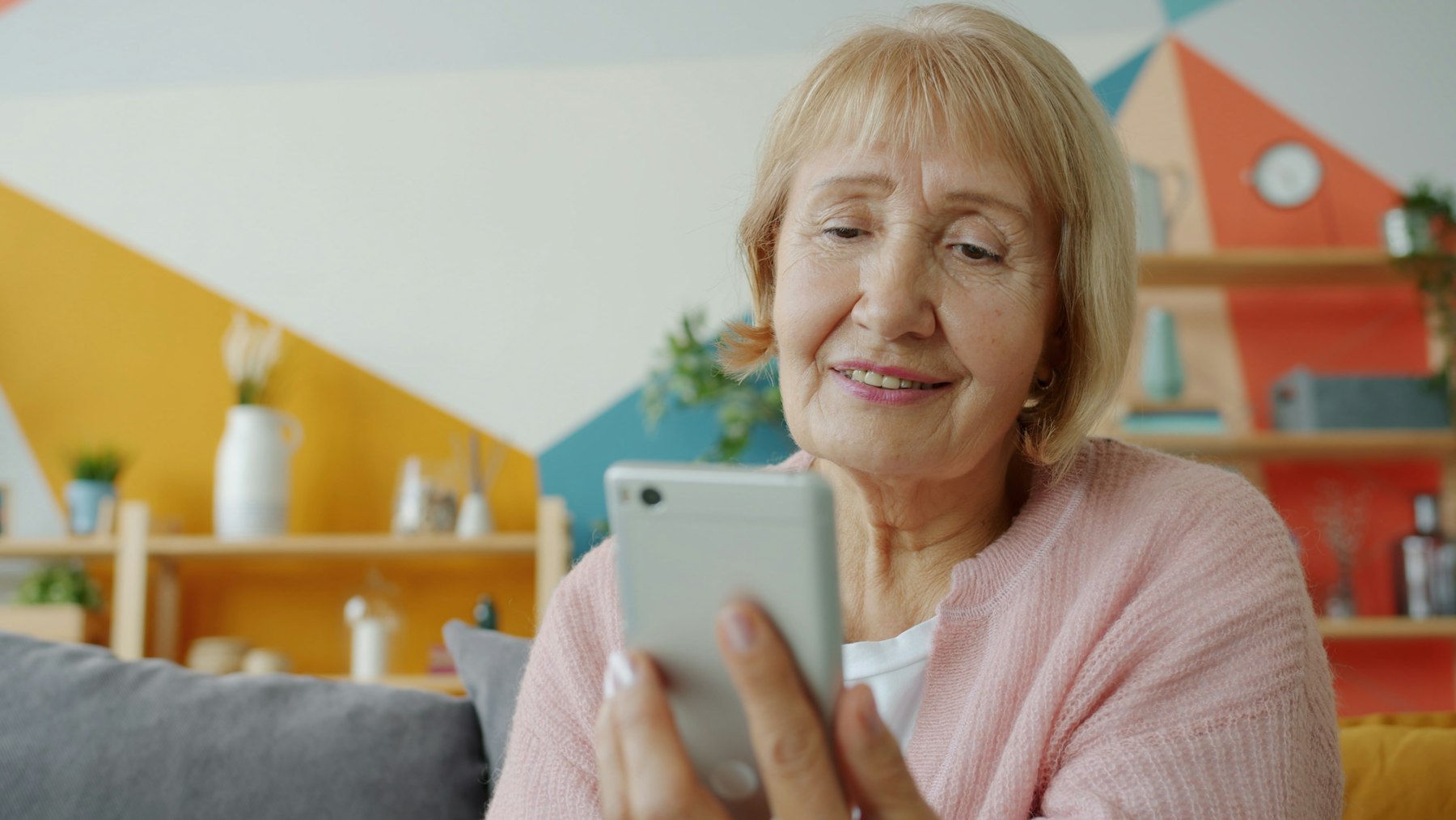 An older woman smiling as she reads a message on her phone