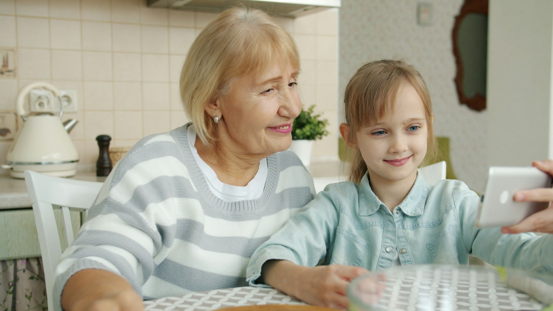 A grandmother and her granddaughter smiling at a phone
